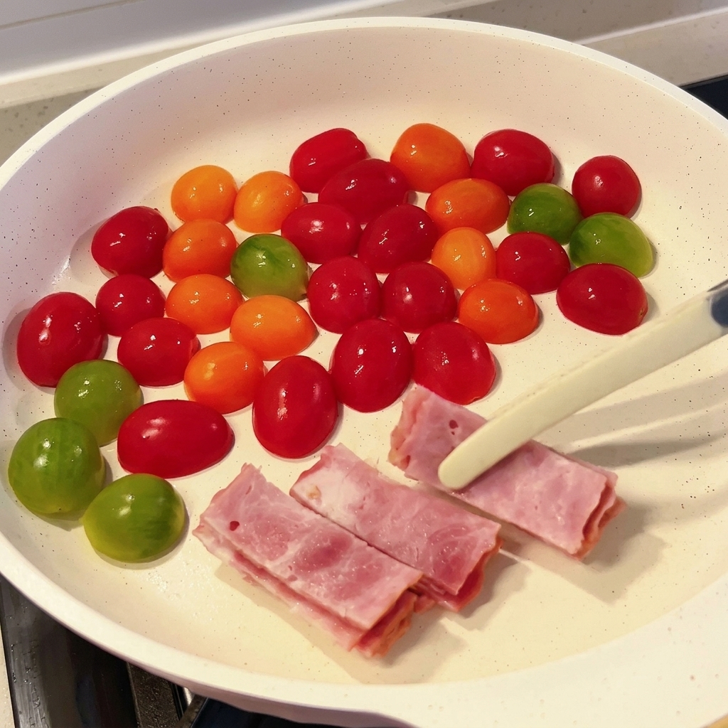 Tiras de bacon siendo añadidas a la sartén con los tomates.