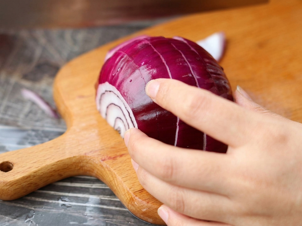 Una cebolla morada picándose en trozos pequeños sobre una tabla de madera.