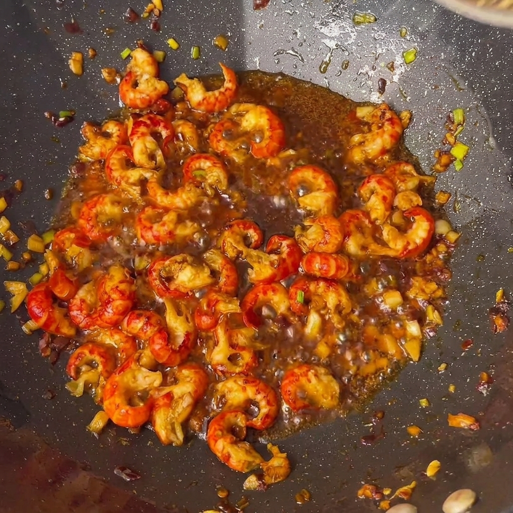 Colas de cangrejo siendo sazonadas con salsas en el wok.