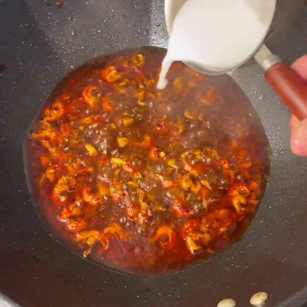 Mezcla de almidón vertida sobre la salsa burbujeante en el wok.