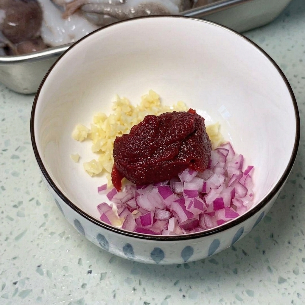 Una sartén metálica ancha con spam, salchichas y tofu cortado, listo para cocinar.