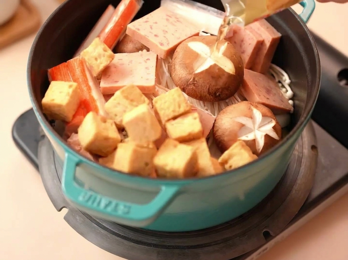 Cubos de tofu de pescado y palitos de cangrejo puestos en la olla.