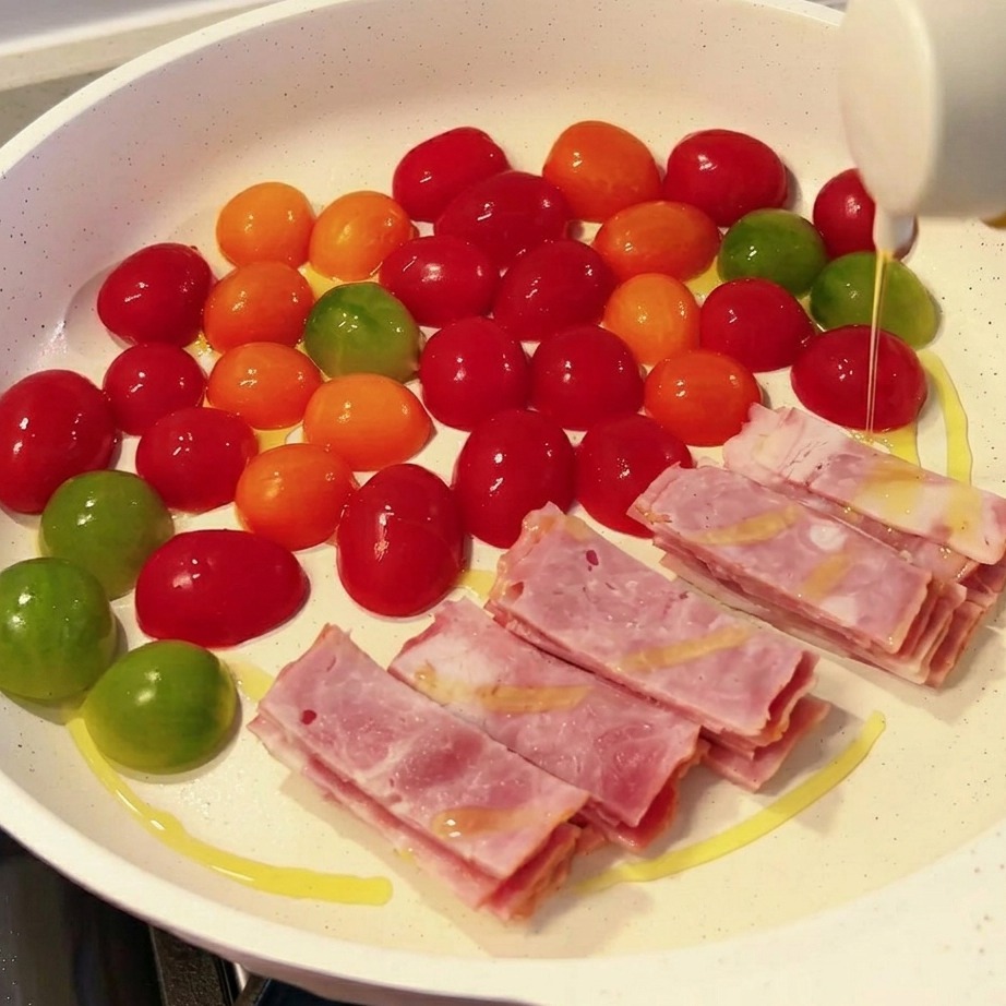 La sartén llena con secciones cuidadosamente organizadas de champiñones enoki, rodajas de spam rosado y bloques de tofu firme blanco.