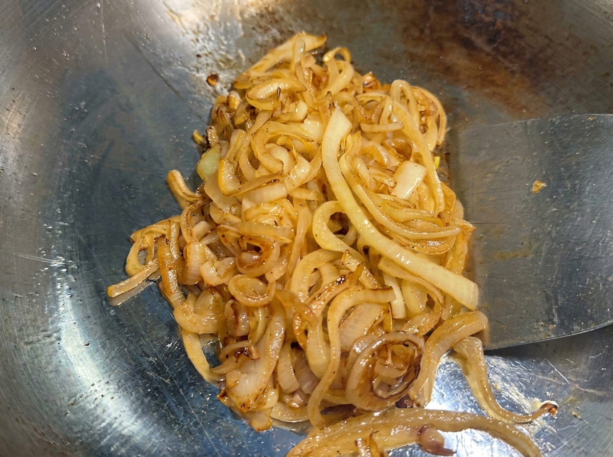 Cebollas en la plancha cocinadas hasta alcanzar un estado de caramelización dorado oscuro.