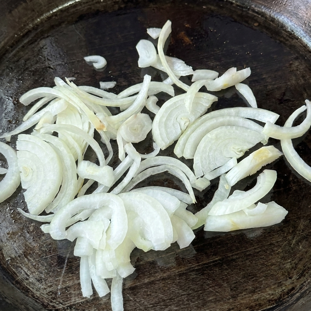 Cebollas crudas en rodajas sobre una plancha engrasada.