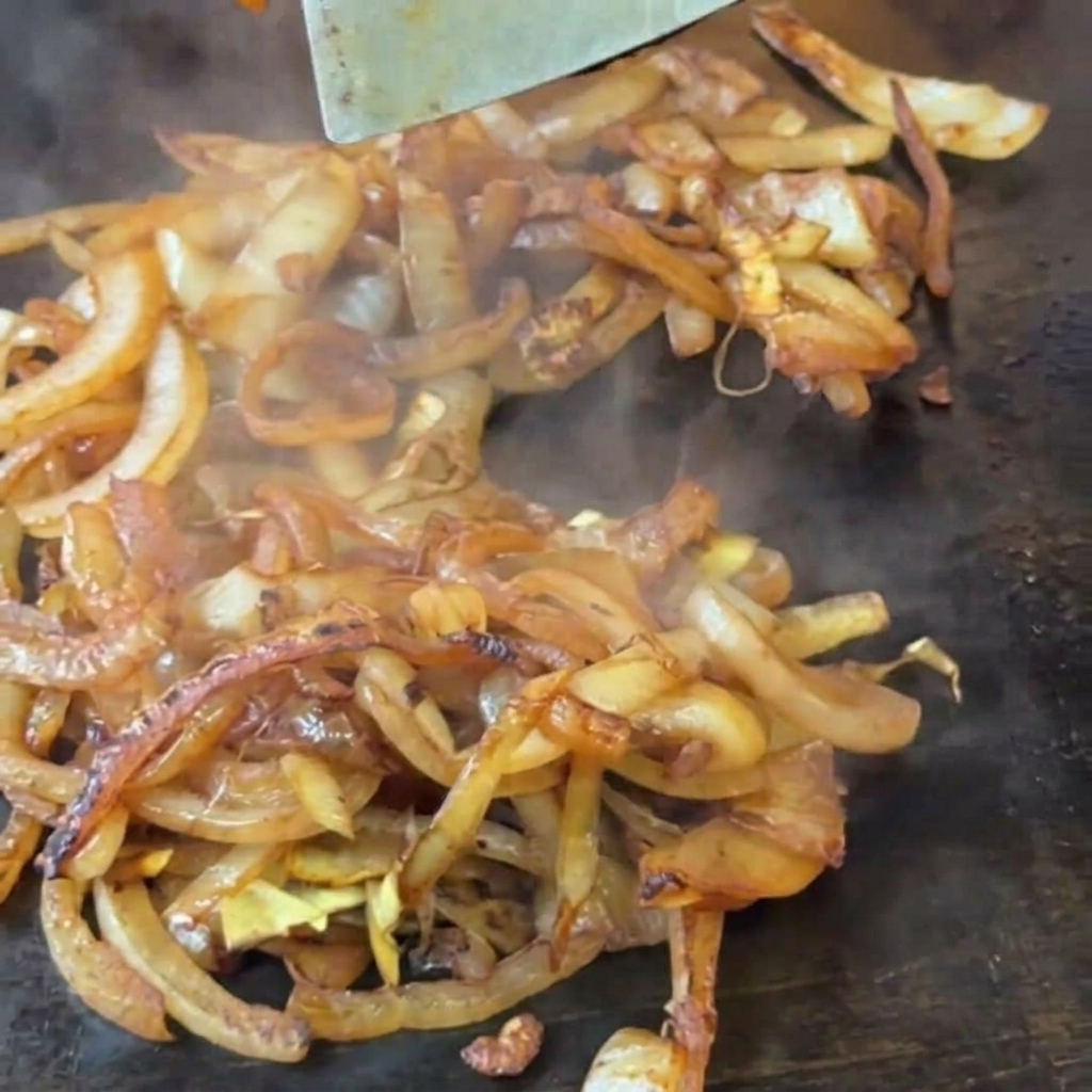 Espátula removiendo cebollas que comienzan a dorarse.