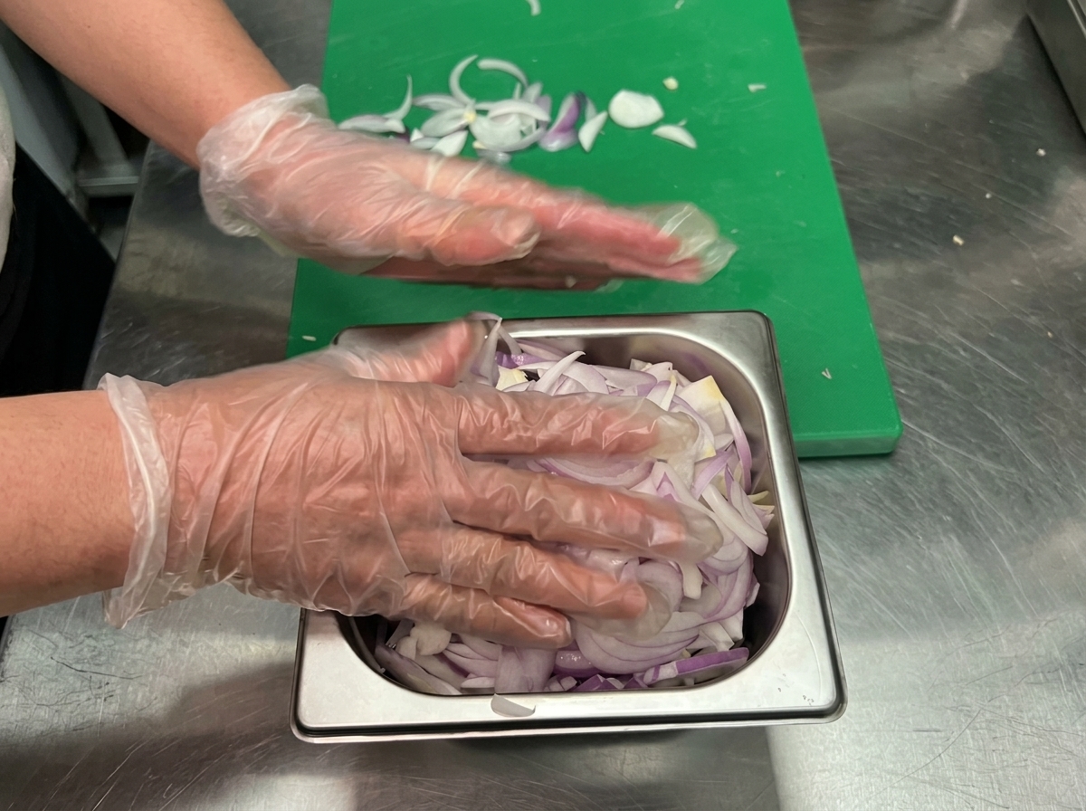 Cebollas salteándose en una sartén con un chorrito de vino tinto y aceite de oliva mientras se mezclan.