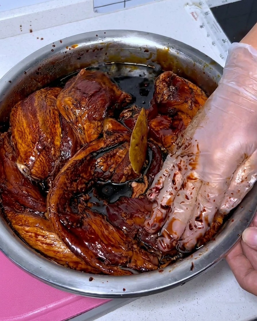 Tiras de panceta fresca siendo limpiadas con baijiu dentro de un bol de acero inoxidable.