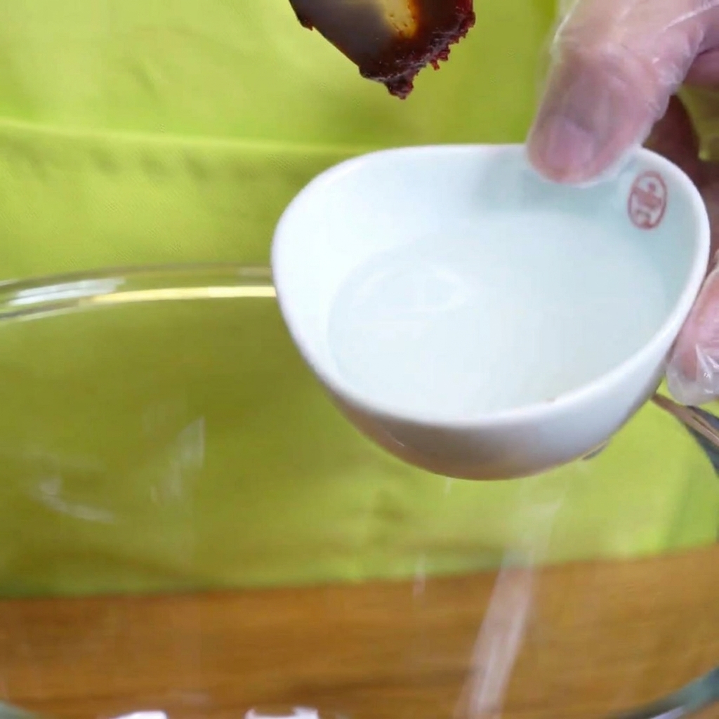 Jarabe de almidón espeso vertiéndose desde una cuchara sobre los ingredientes del marinado.