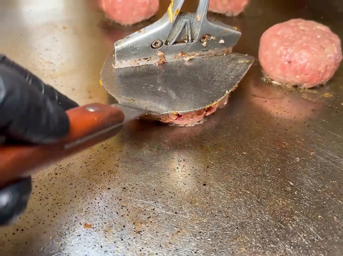 Hamburguesas de ternera chisporroteando en la plancha.