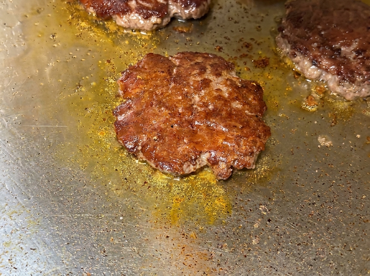 Primer plano de queso fundido sobre las hamburguesas de ternera en la plancha.