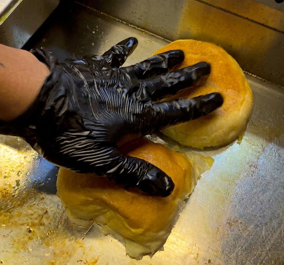 Una hamburguesa de ternera cruda sazonada colocada en una plancha caliente.