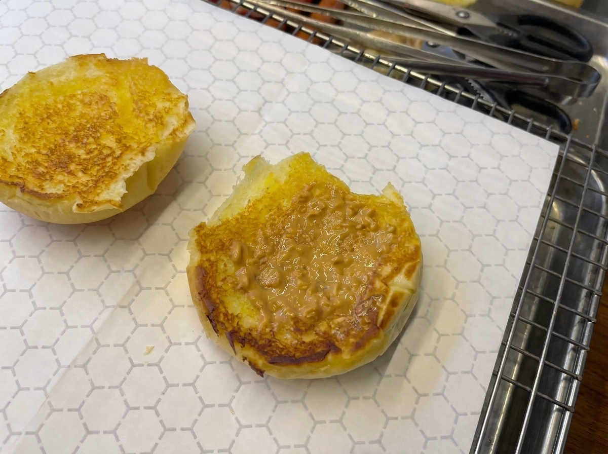 Primer plano de un pan tostado con salsa siendo sellado con un soplete de cocina.