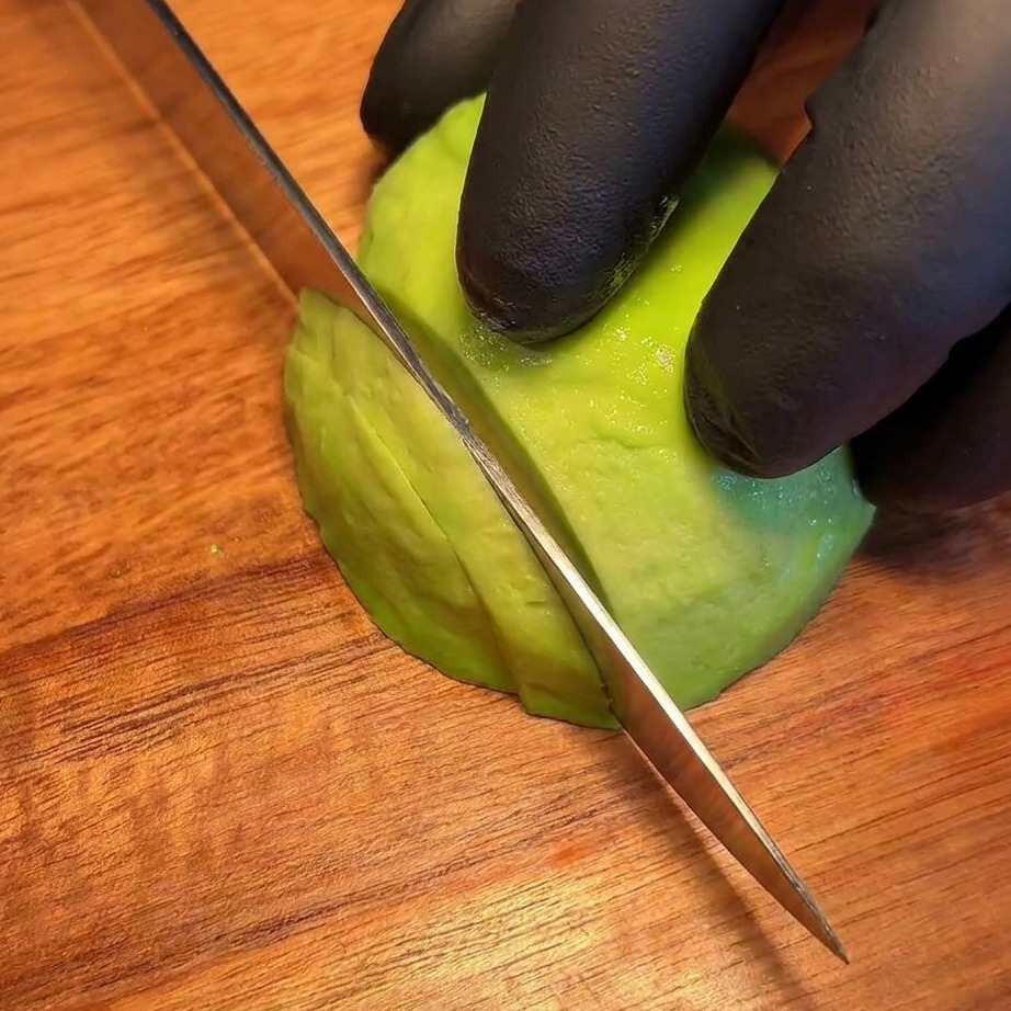 Láminas finas y uniformes de aguacate fresco ordenadas sobre una tabla.