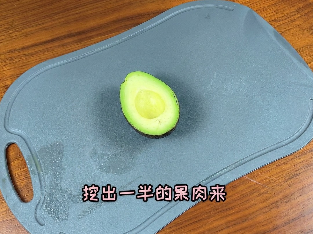 Un aguacate cortado por la mitad sobre una tabla de cortar, listo para ser rebanado.