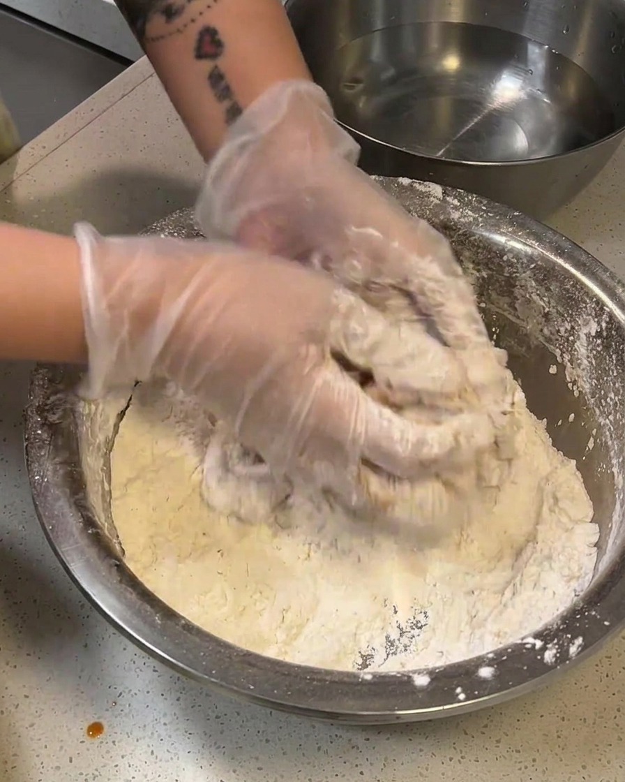 Un filete de pollo enharinado sumergiéndose brevemente en un bol con agua.