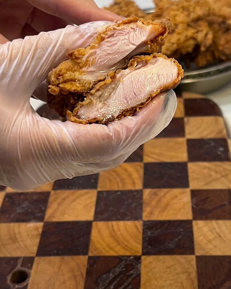 Un filete de pollo frito cortado a la mitad, mostrando el interior jugoso.