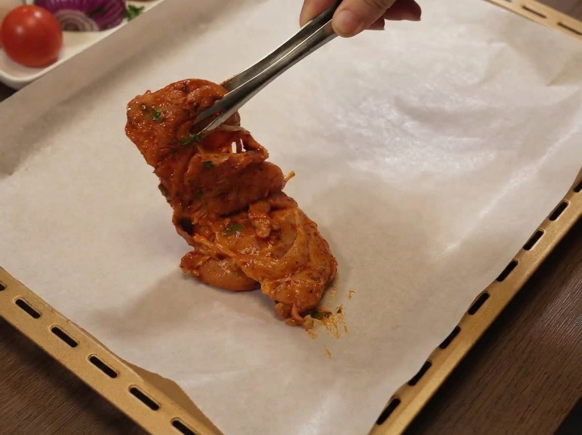 Muslos de pollo crudos marinados colocados en una bandeja de horno forrada con papel pergamino.