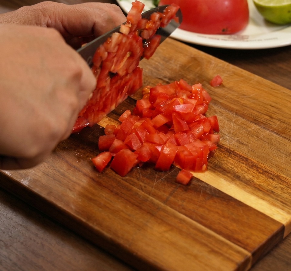 Primer plano de tomates picados, cebollas rojas y cilantro siendo mezclados en un tazón.