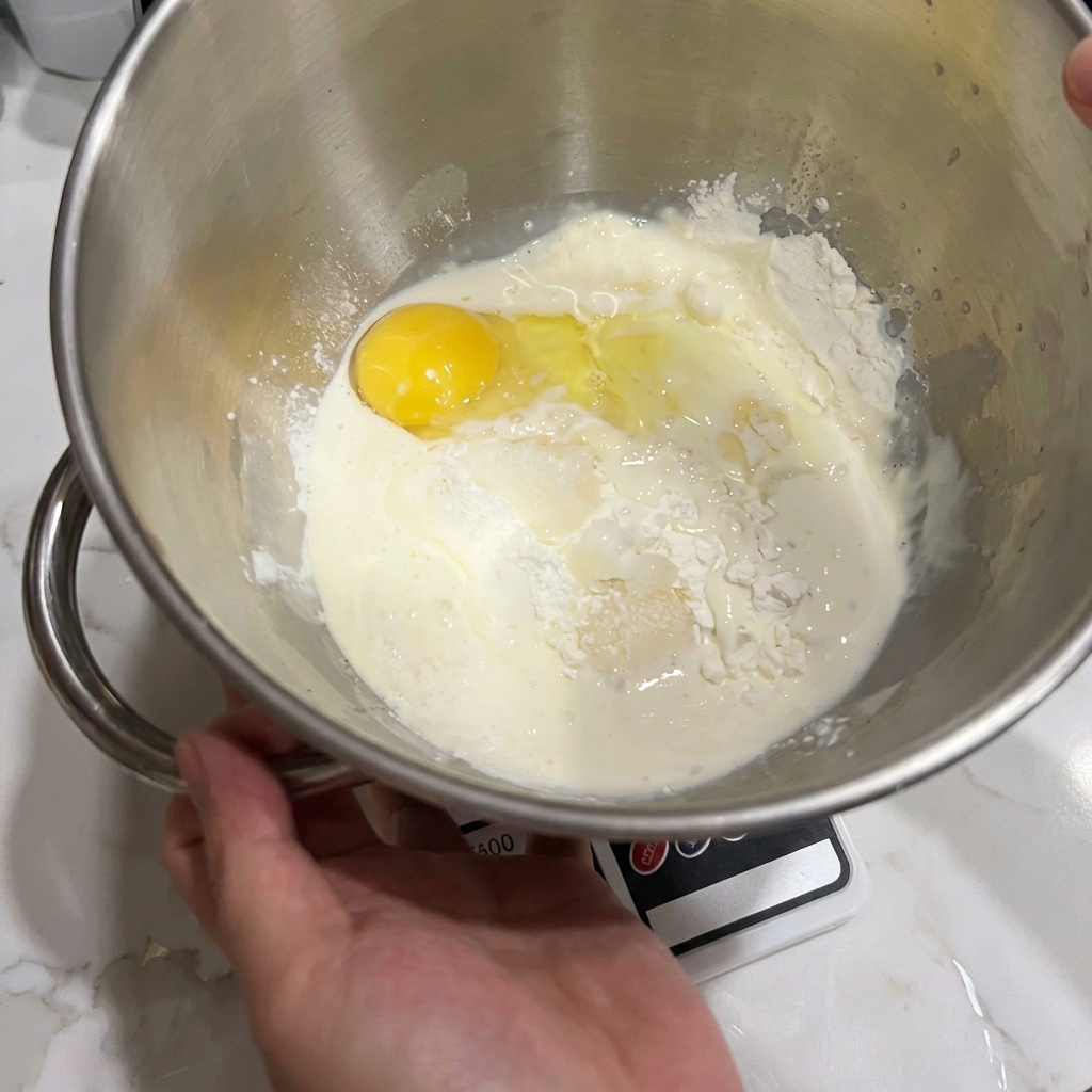Tazón de batidora con harina, huevo y leche listos para mezclar.
