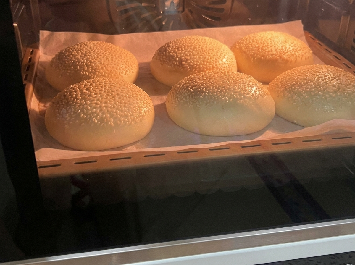 Seis panes de hamburguesa horneados sobre una bandeja.