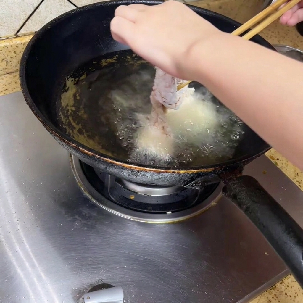 Bajando pollo al aceite caliente en un wok.