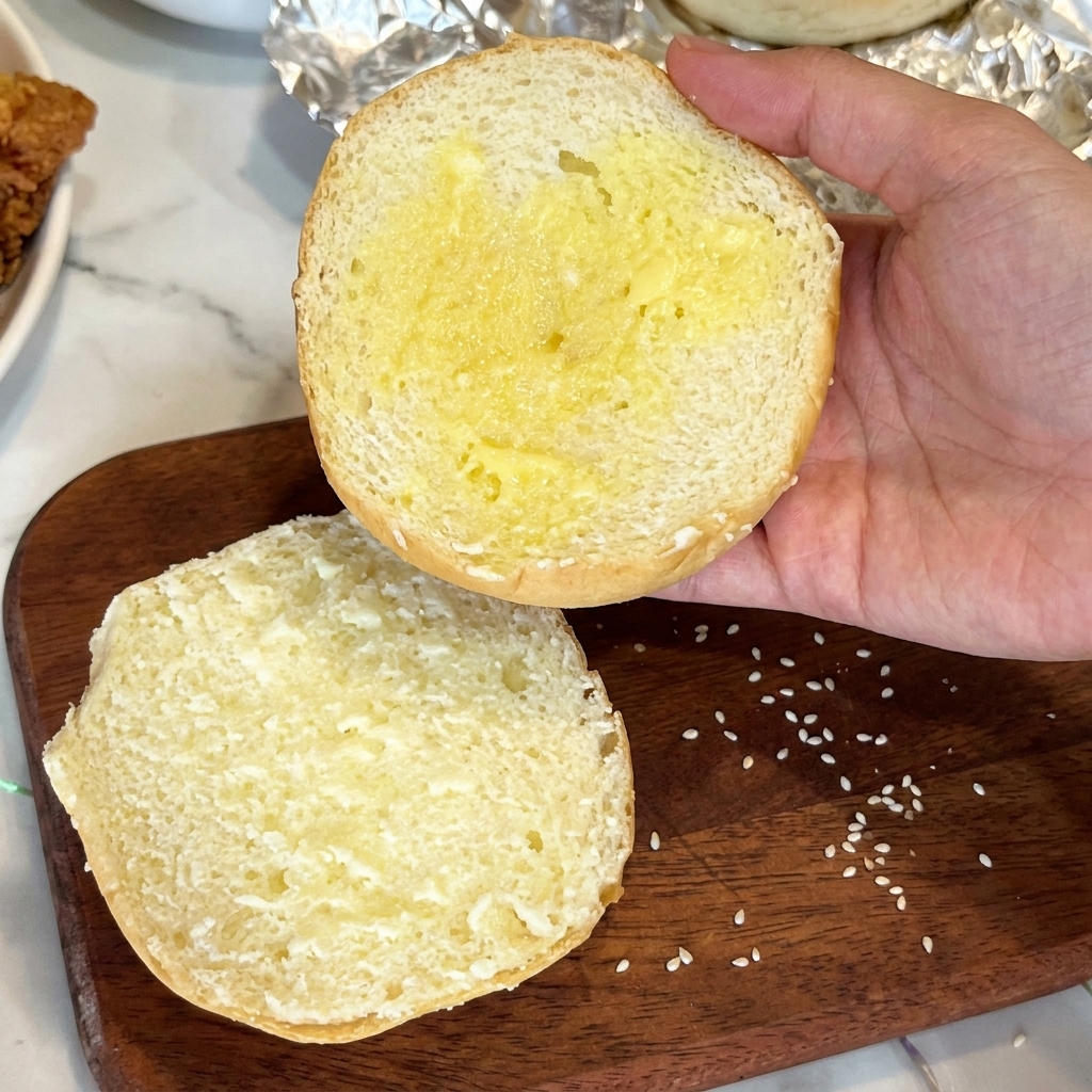 Pan de hamburguesa untado con mantequilla derretida.