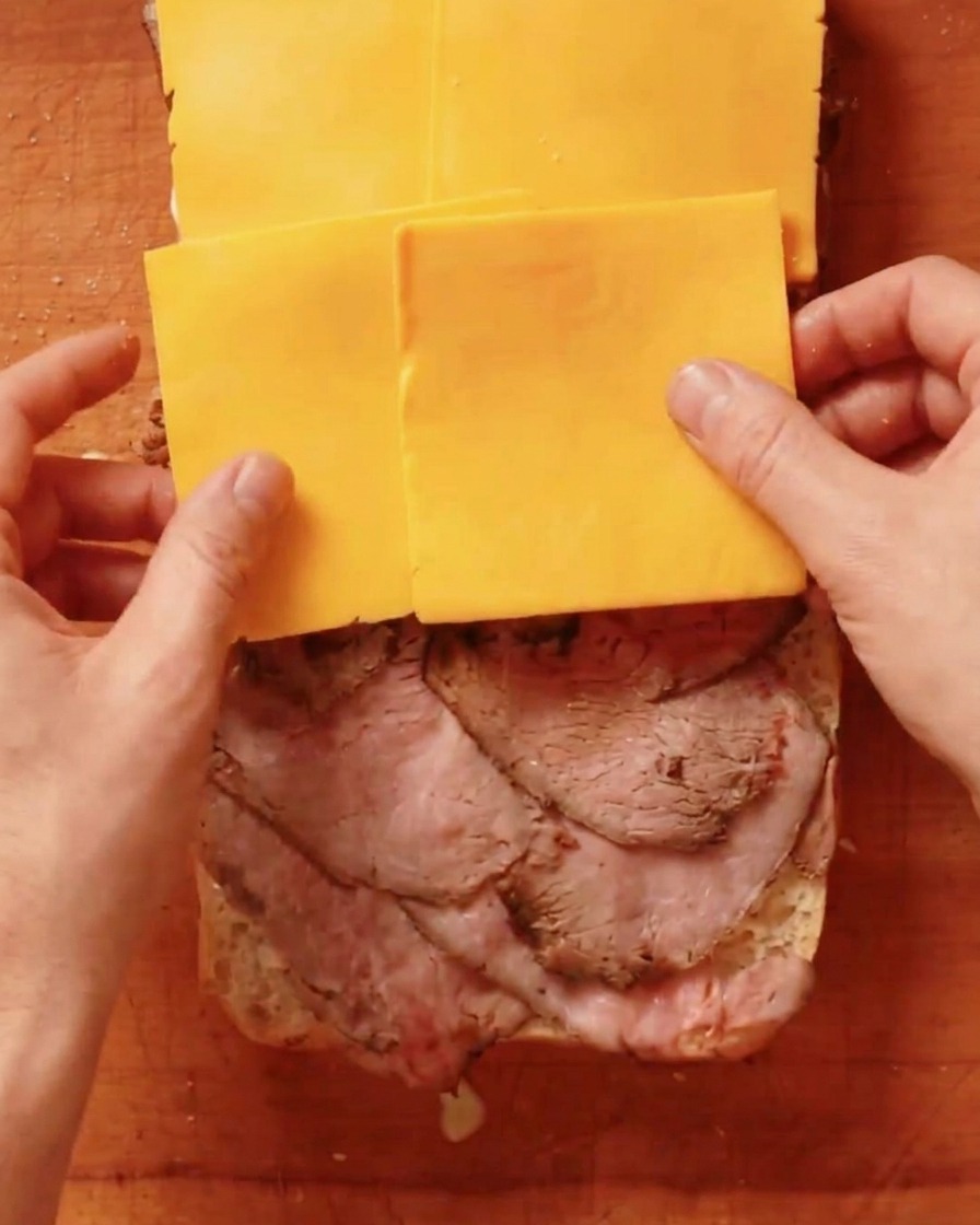 Lonchas de queso cheddar amarillo puestas sobre una capa de roast beef.