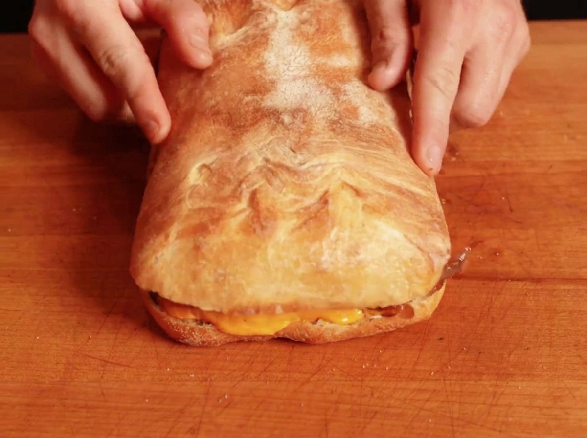 La parte superior del pan siendo colocada sobre el sándwich relleno.