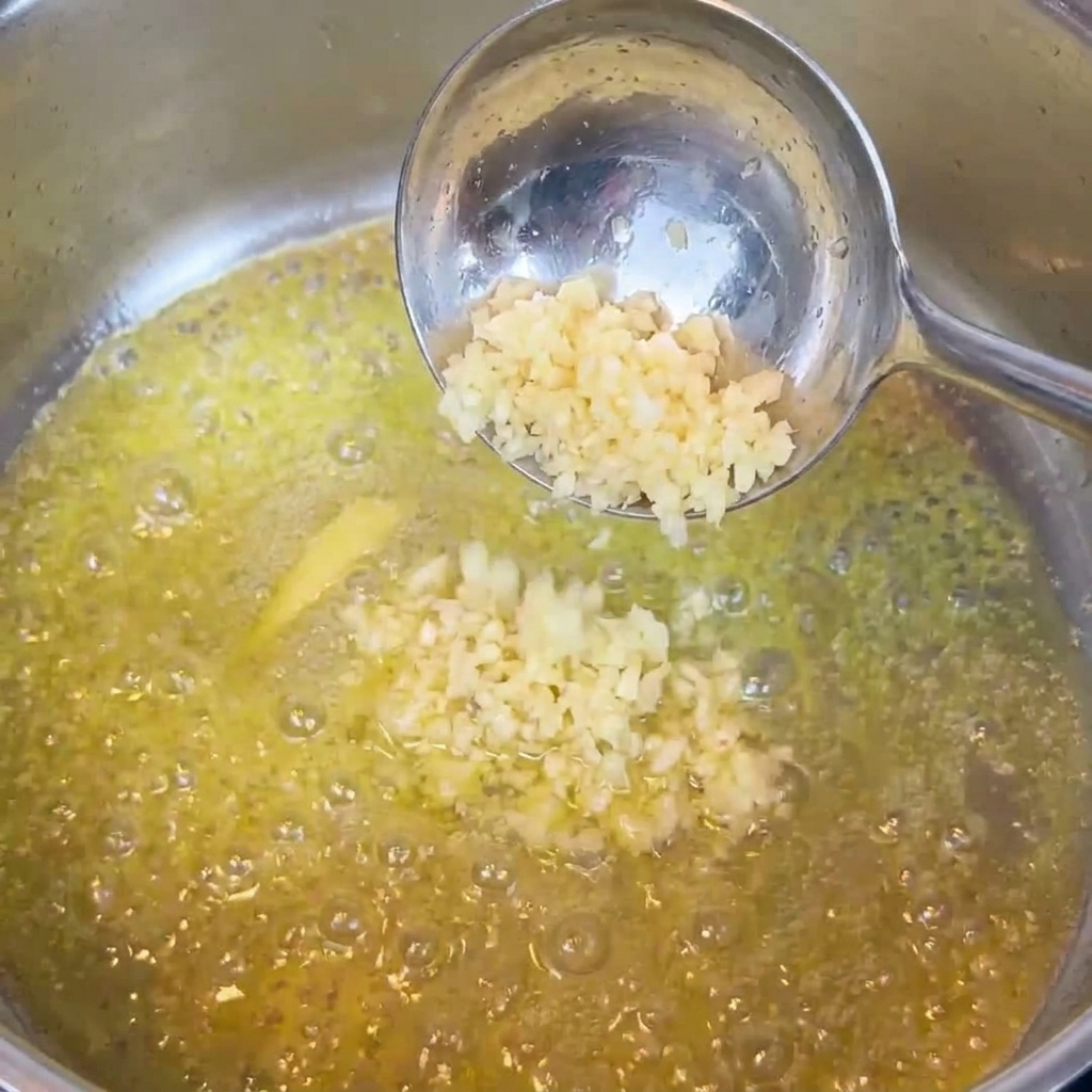 Ajo picado siendo removido en mantequilla derretida en una sartén.