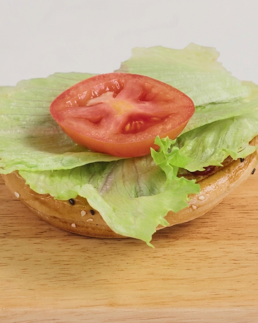 Una hamburguesa recién montada con lechuga, carne con queso y salsa barbacoa, lista para servir.