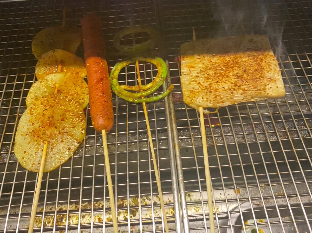 Rodajas de patata, salchicha y vegetales a la parrilla cubiertos con una brillante salsa barbacoa y copos de chile.
