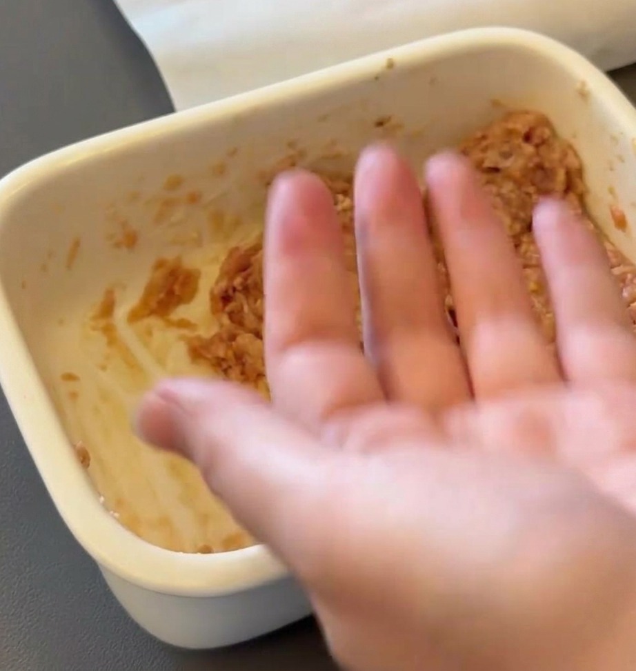 Una mano dando forma redonda a la mezcla de carne cruda.