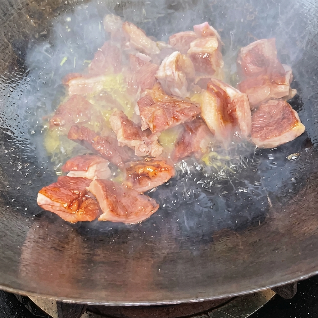 Trozos de costilla salteándose en un wok cubiertos por un glaseado de caramelo oscuro.
