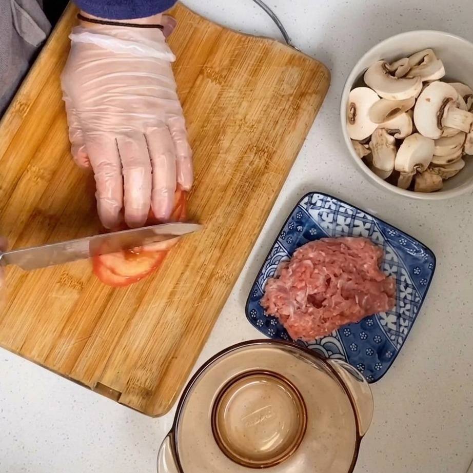 Un tomate pelado siendo picado en una tabla de cortar de madera.
