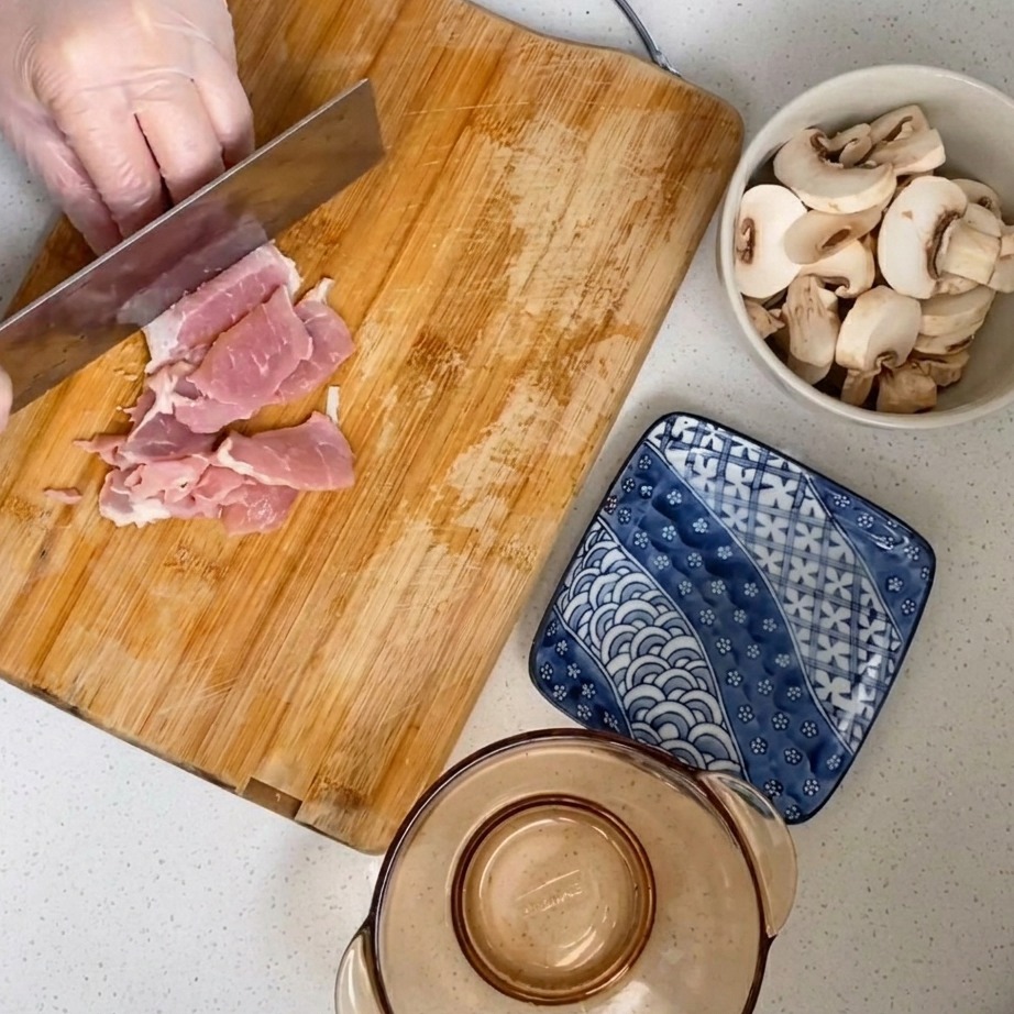 Carne de cerdo cruda siendo picada finamente en una tabla de madera.
