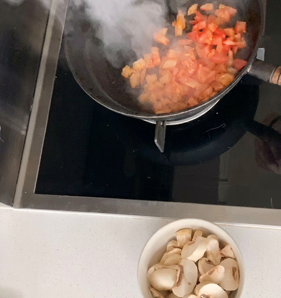 Tomates picados siendo salteados en una sartén negra.