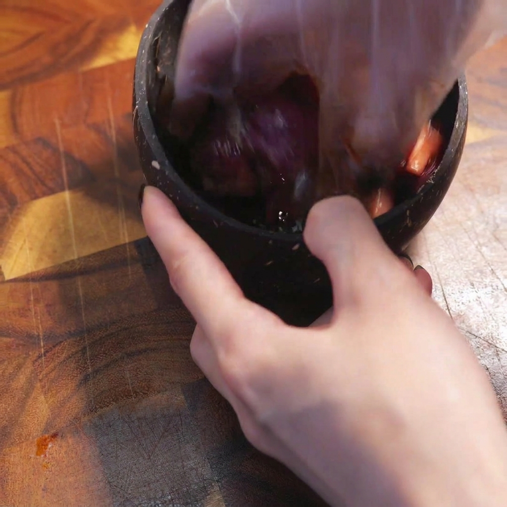 Una mano con guante mezclando la carne con los condimentos en un bol.