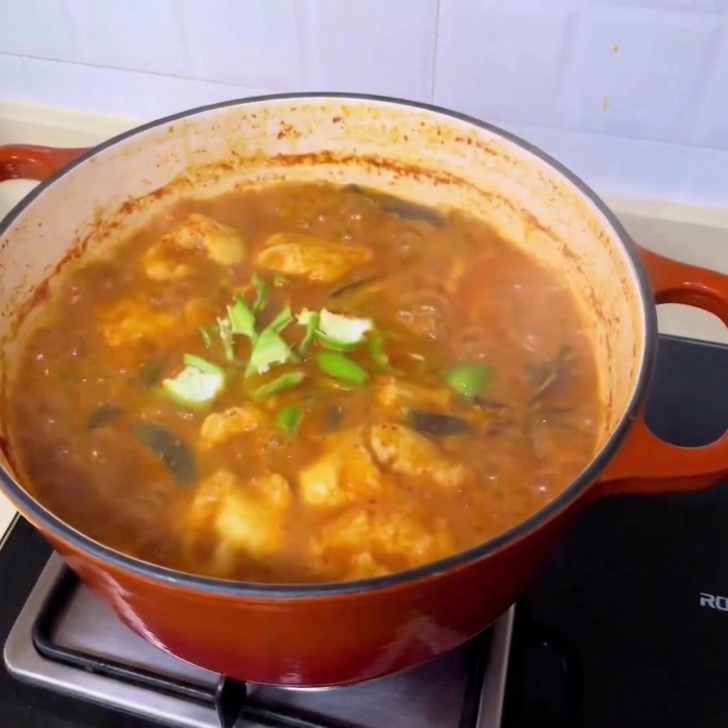 Rodajas de chile verde fresco esparciéndose sobre la rica y burbujeante sopa de almejas al estilo coreano.