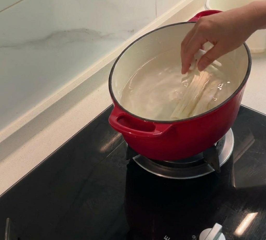 Pelos y mazorcas de maíz, junto con pieles de pollo, hirviendo a fuego lento en una olla con agua para crear un caldo sabroso.