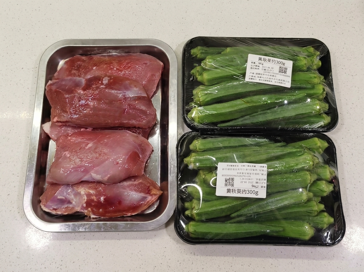 Paquetes de pechuga de pato cruda y okra fresca entera sobre una encimera blanca.