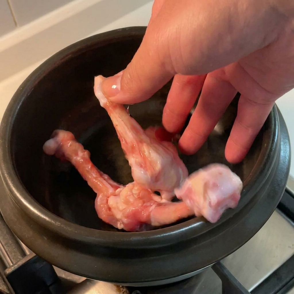 Huesos de pollo deshuesados en una olla de cerámica negra.
