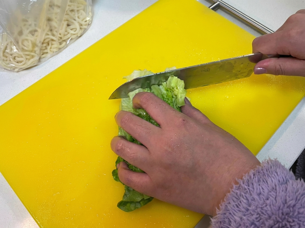 Lechuga verde cortada en una tabla amarilla.