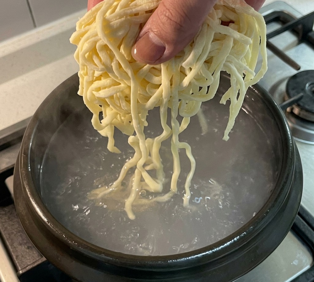 Fideos frescos añadidos a la olla con caldo.
