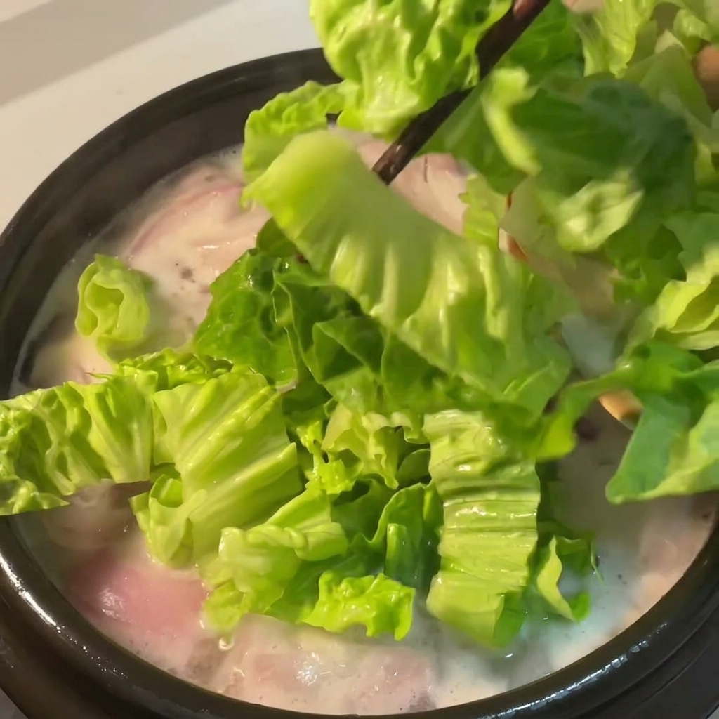 Lechuga fresca incorporándose a la sopa hirviendo.