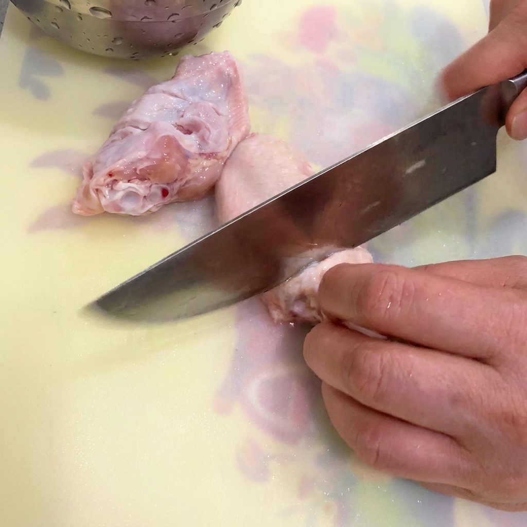 Alitas de pollo, jengibre y cebolleta en una olla con agua fría listos para ser blanqueados.