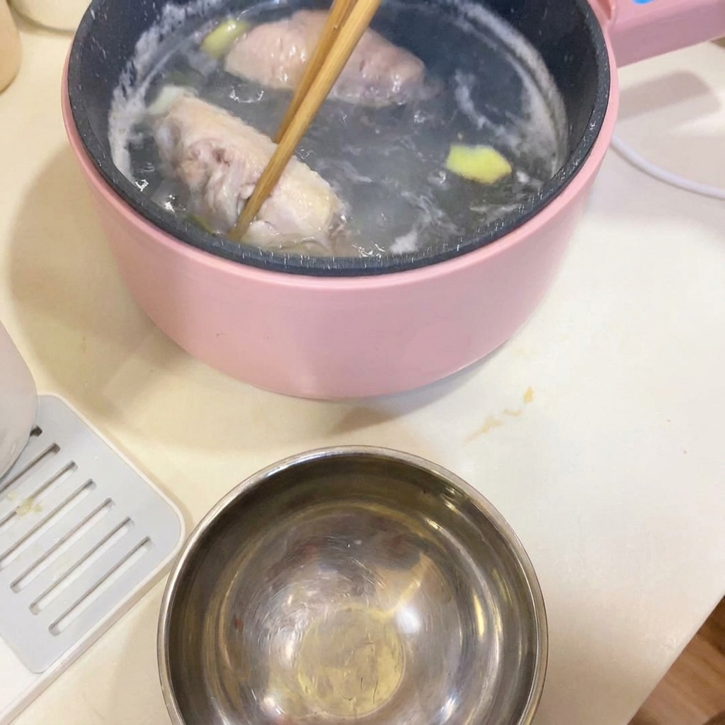 Palillos sacando las alitas de pollo blanqueadas de la olla de cocción.