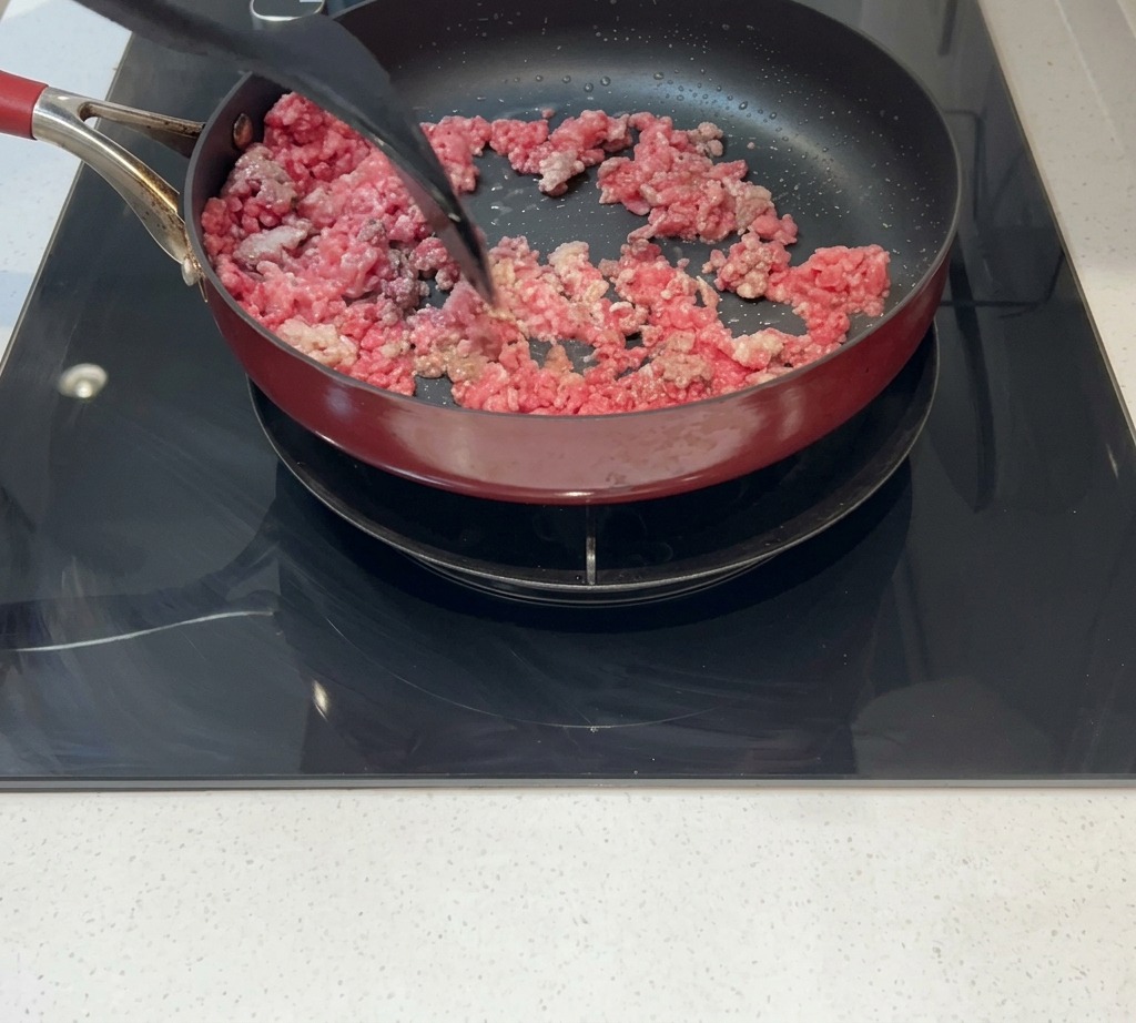 Carne picada removida en una sartén hasta quedar dorada y bien cocinada.