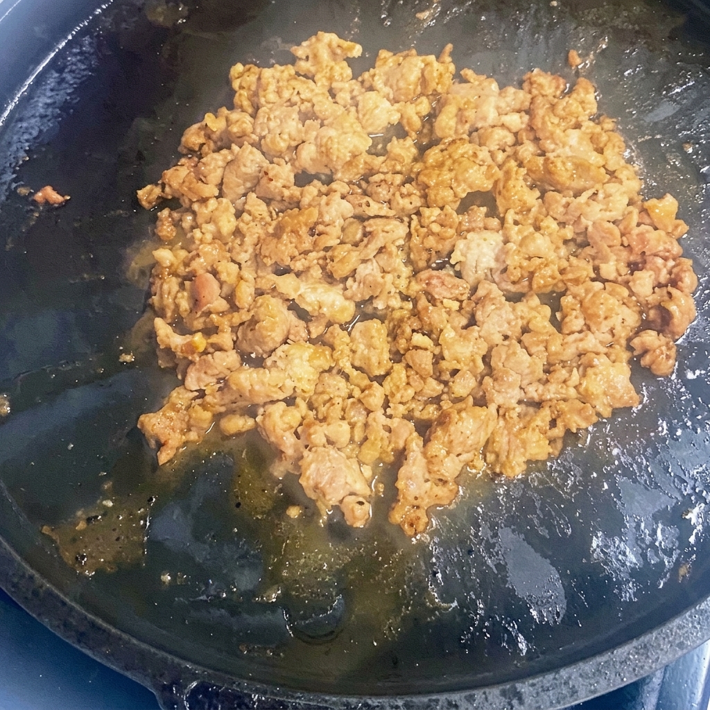 Carne molida dorándose en una sartén de hierro caliente.