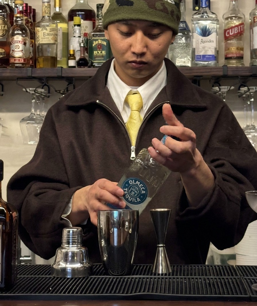 Tequila siendo medido en un jigger y vertido en una coctelera.
